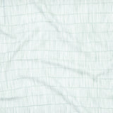 Close up of gently draped printed linen with thin hand drawn stripe grid in ivory on light blue.