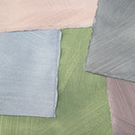 Pile of wallpaper swatches with irregular brushed patterns in shades of blue, green, gray and pink.