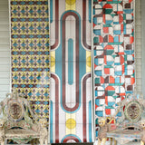 Porch setting with three panels of wallpaper with geometric stained glass patterns and ornate chairs.