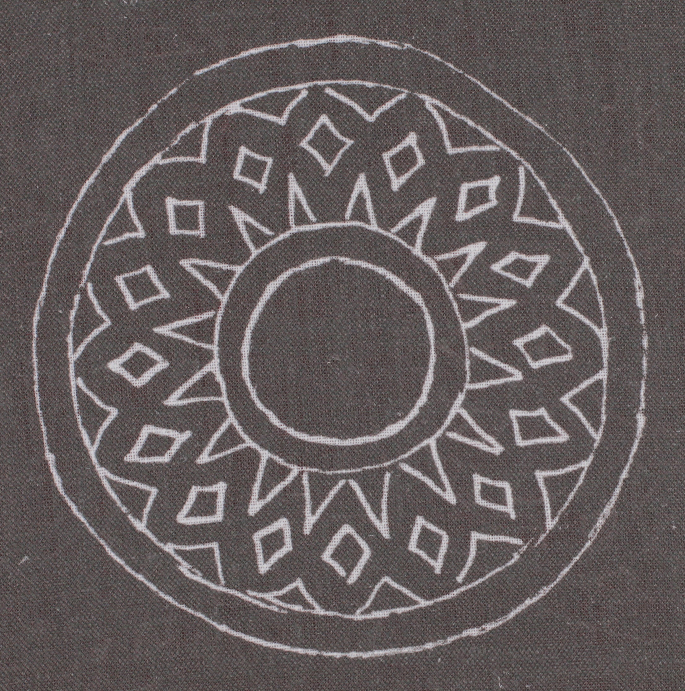 Detail of fabric in a repeating circular geometric print in light gray on a charcoal field.