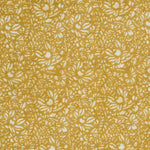 Detail of a printed linen fabric in a repeating chrysanthemum pattern in white on a mustard field.