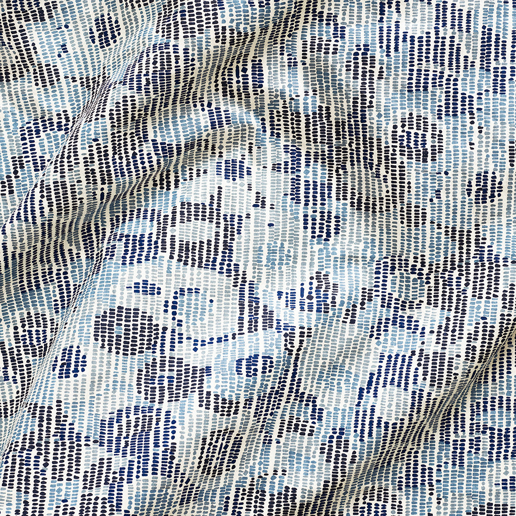 A close up of gently draped printed fabric with a pointillist abstract floral pattern in shades of blue on white. 