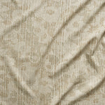 A close up of gently draped printed fabric with a pointillist abstract floral pattern in beige and taupe on white. 
