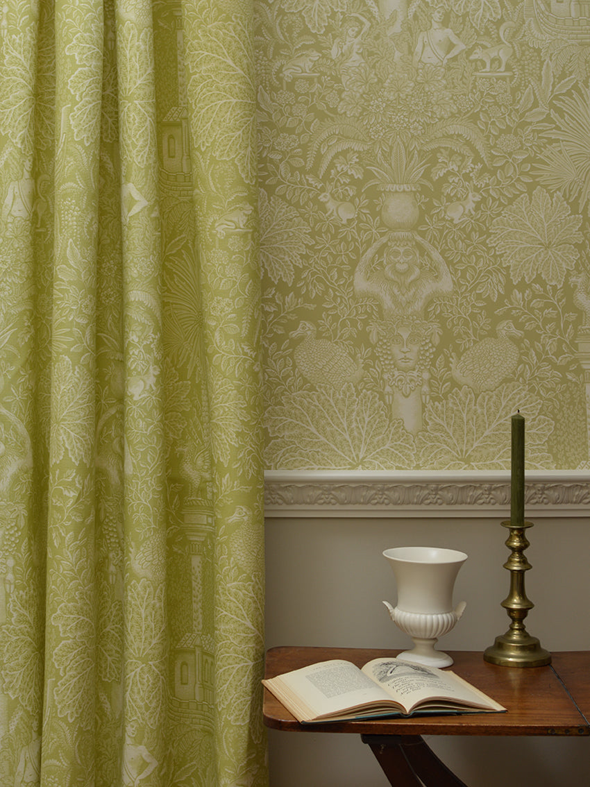 Room with green patterned wallpaper and a table with an open book and decorative items.