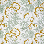 Detail of fabric in an intricate floral print in mustard and green on a white field.