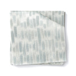 Stacked swatches of fabric in a linear check pattern in shades of pastel aqua blue on a white background