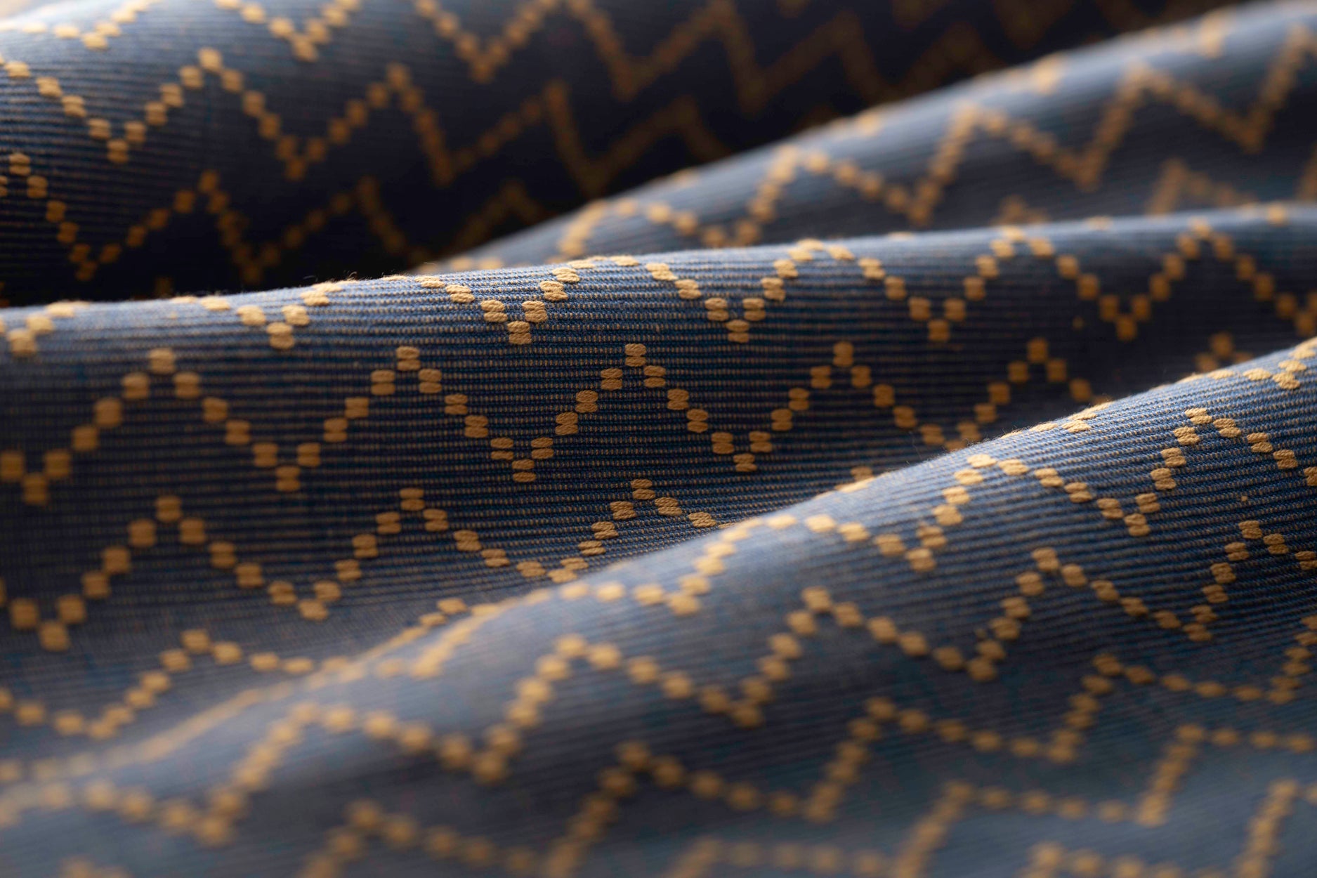 Lightly folded patterned fabric with tan zigzag design on a navy background