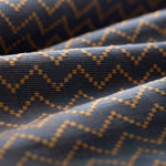 Lightly folded patterned fabric with tan zigzag design on a navy background