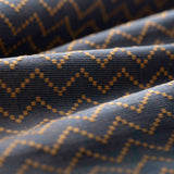 Lightly folded patterned fabric with tan zigzag design on a navy background
