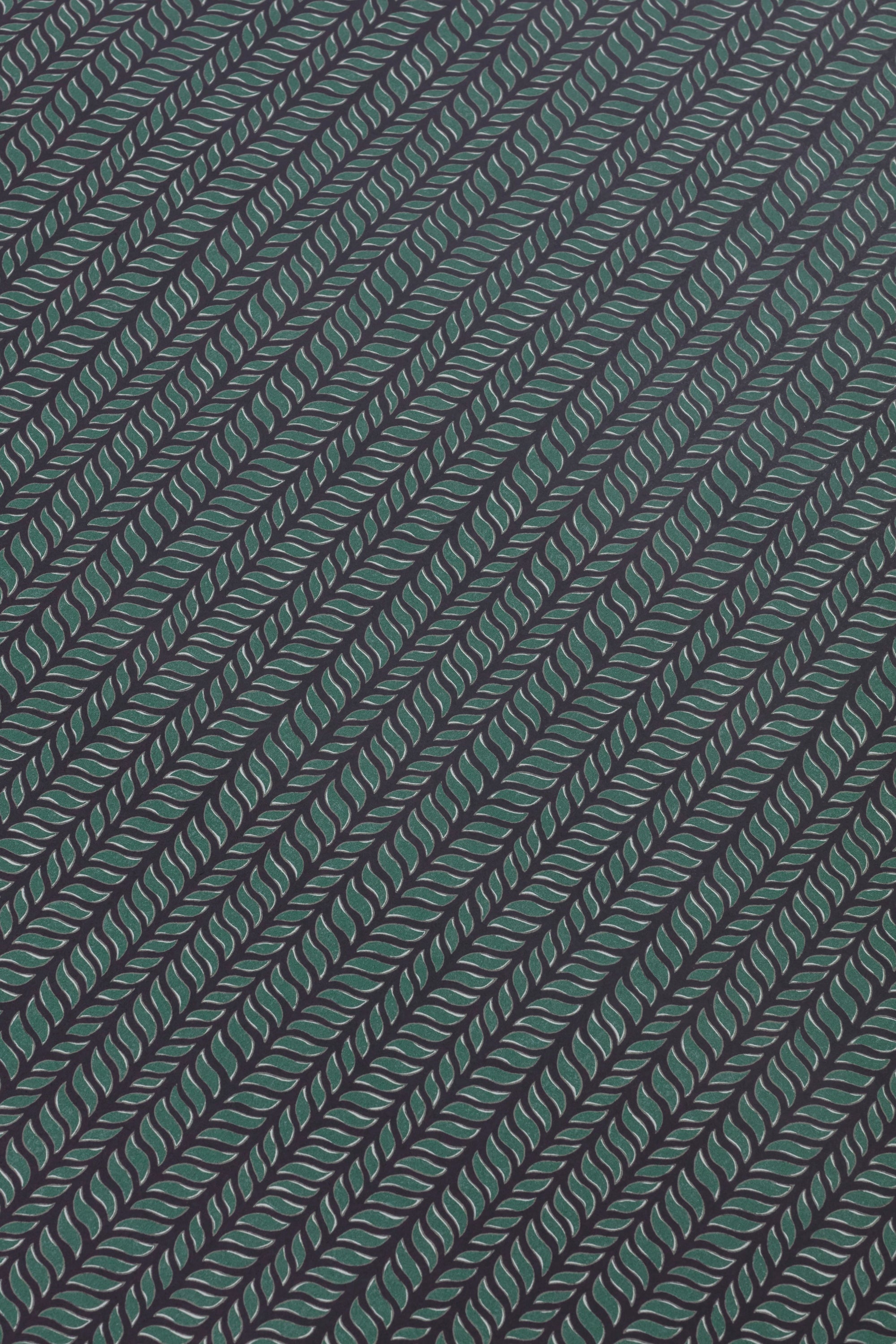 Detail of a wallpaper panel in a painterly herringbone print in green and light blue on a navy field.