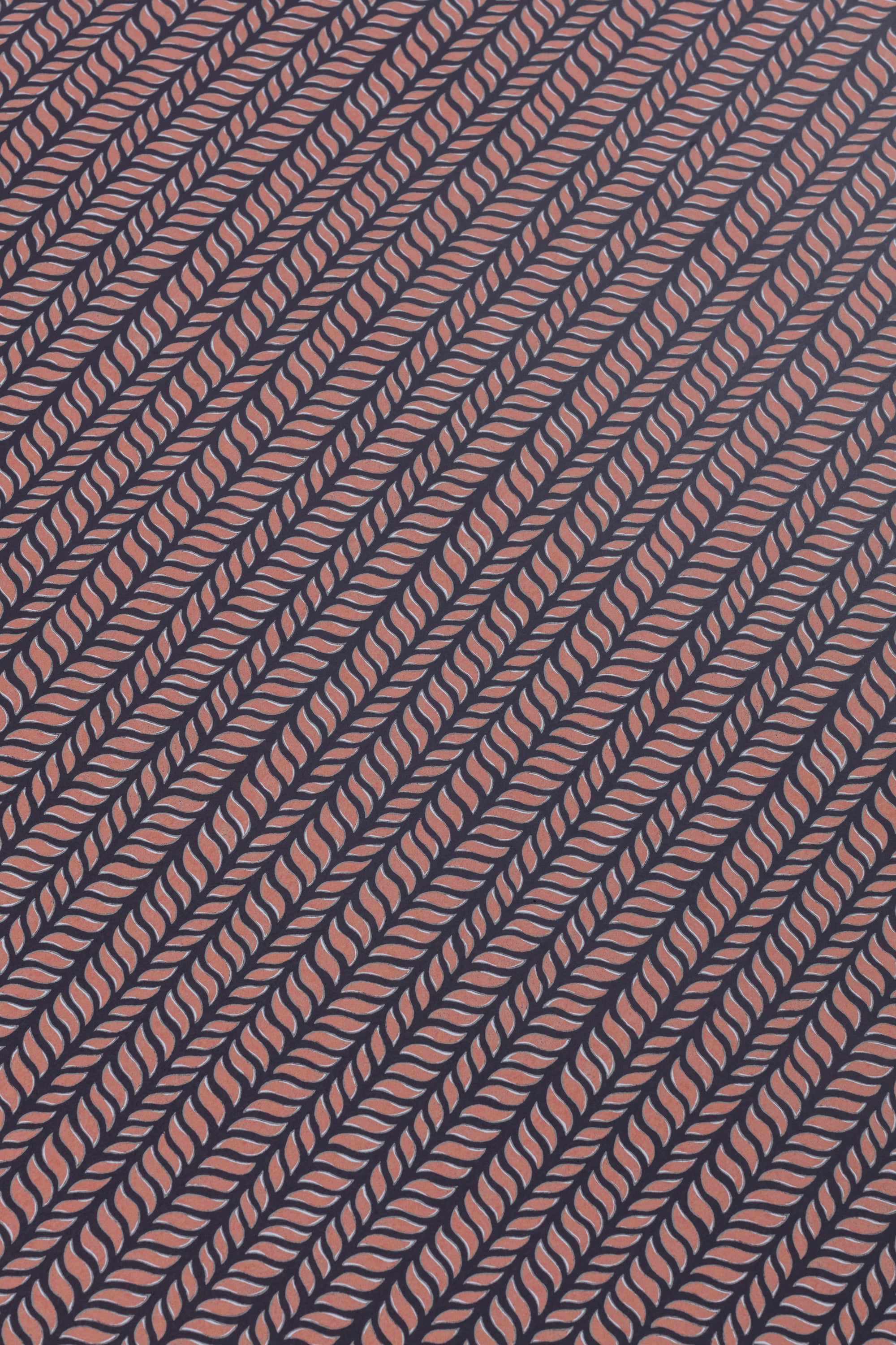 Detail of a wallpaper panel in a painterly herringbone print in pink on a navy field.