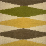 Close-up of a patterned rug with geometric shapes in green, brown, and beige.
