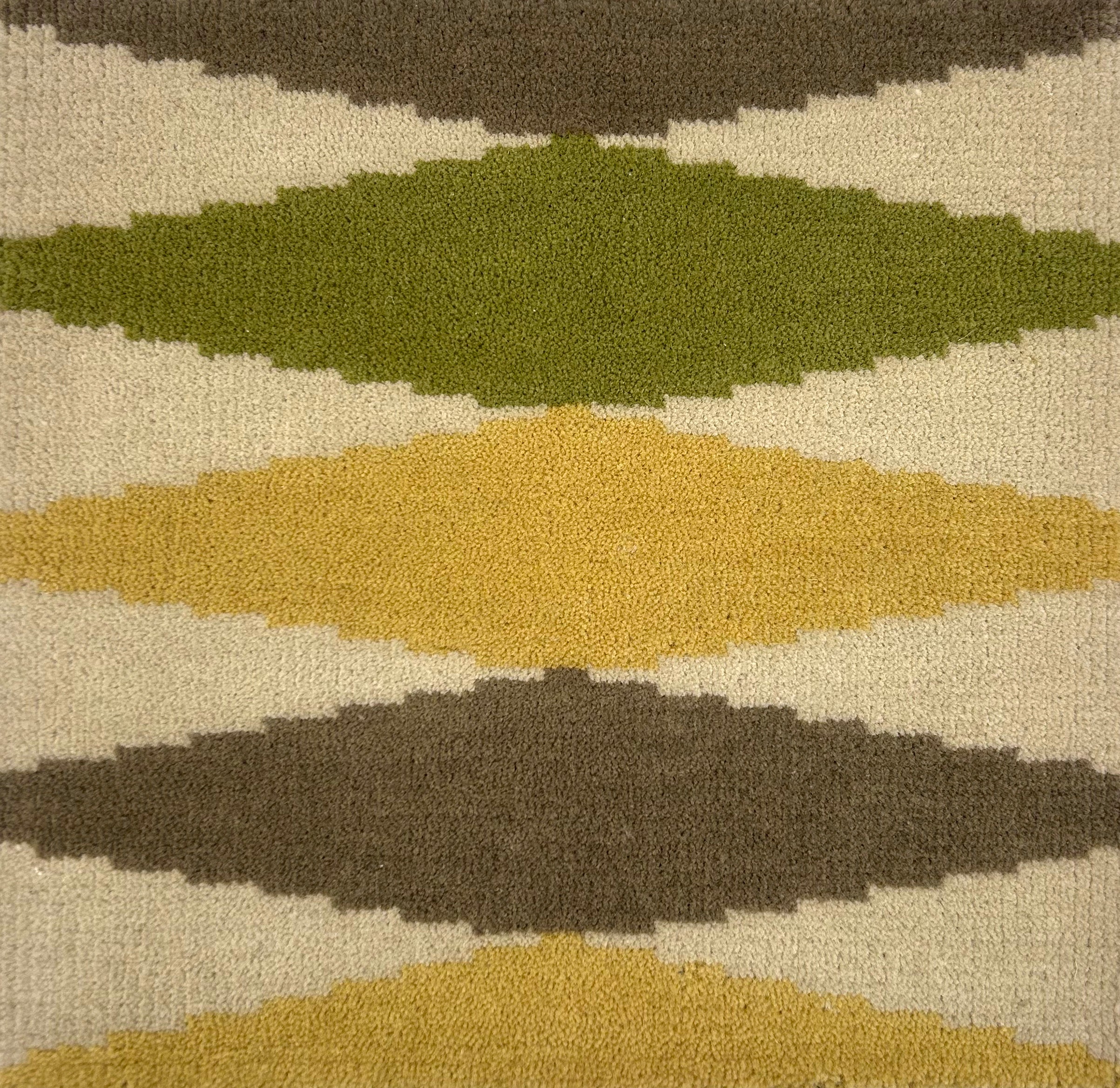 Close-up of a patterned rug with geometric shapes in green, brown, and beige.