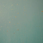 Detail of a wallpaper in a random splattered pattern in metallic gold on a green field.