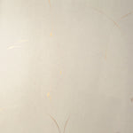 Detail of a wallpaper in an elongated paint splatter pattern in metallic gold on a cream field.