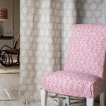 Close-up of a living room with a hanging curtain in a floral lattice print in white and cream on a tan field.