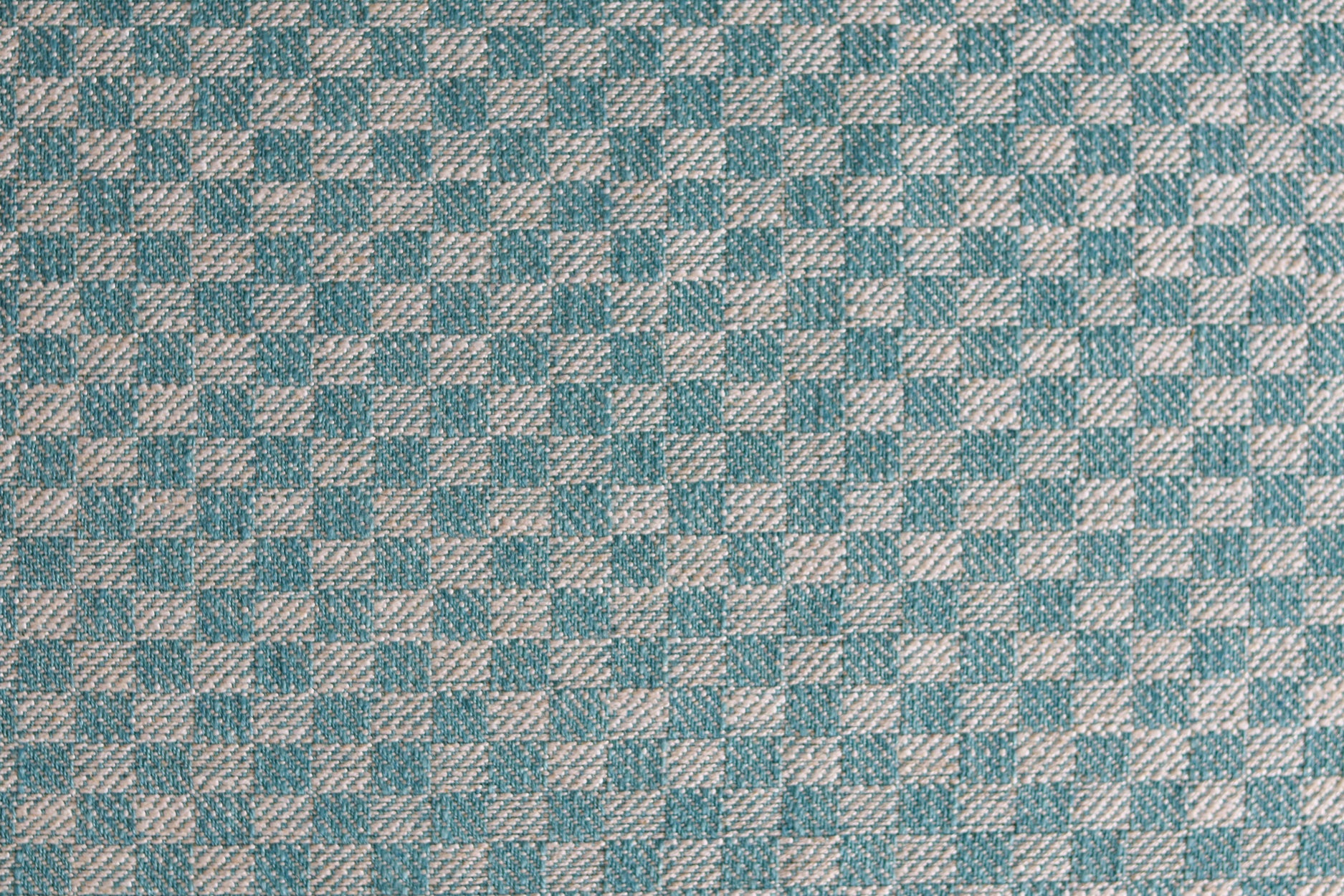 Close up of woven fabric with small scale checkerboard pattern in white and turquoise. 