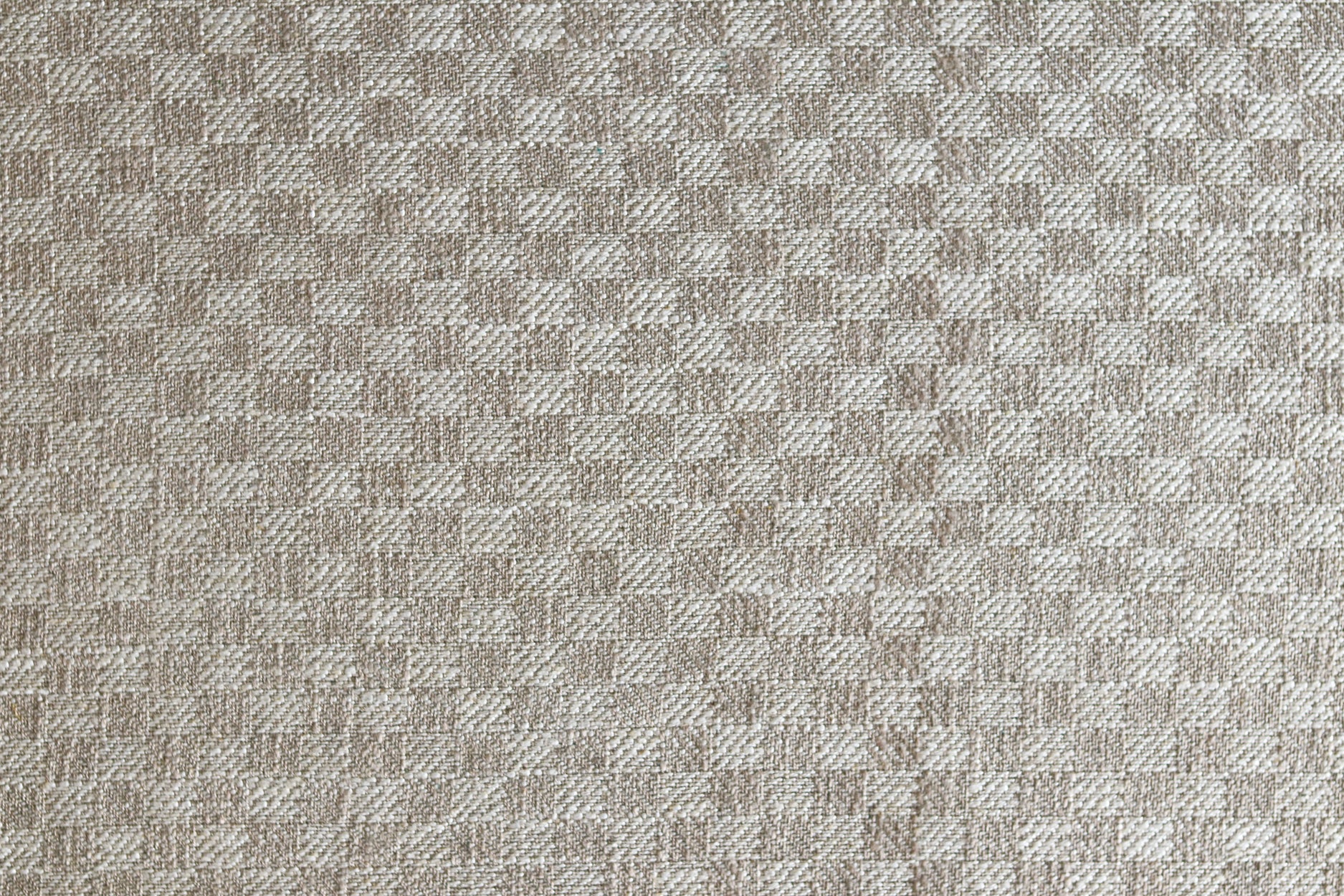 Close up of woven fabric with small scale checkerboard pattern in white and beige.