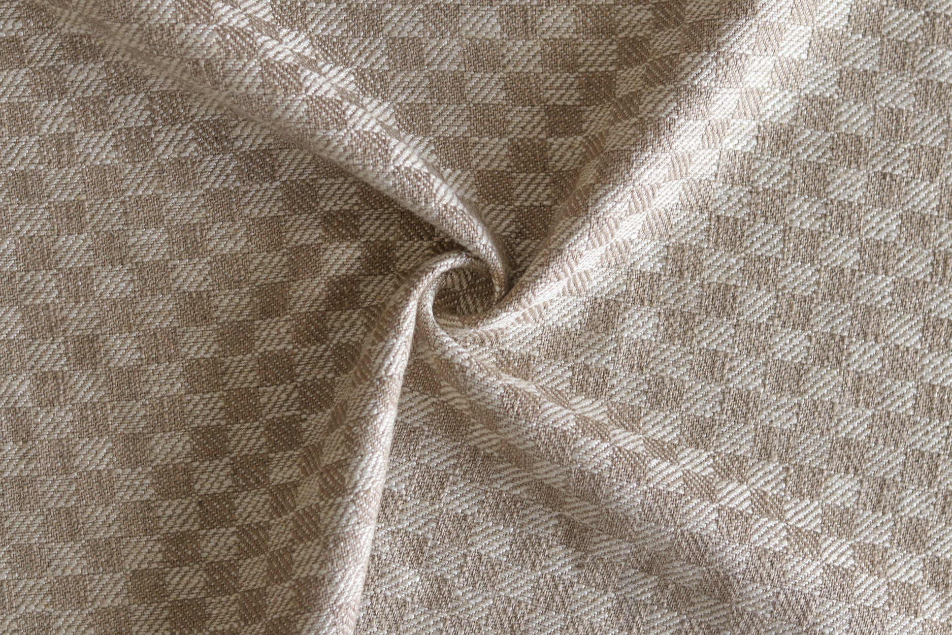 Close up of draped woven fabric with small scale checkerboard pattern in white and beige.