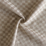 Close up of draped woven fabric with small scale checkerboard pattern in white and beige.