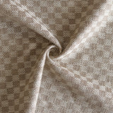 Close up of draped woven fabric with small scale checkerboard pattern in white and beige.