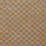 Close up of woven fabric with small scale checkerboard pattern in white and light orange.