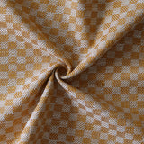 Close up of draped woven fabric with small scale checkerboard pattern in white and light orange.