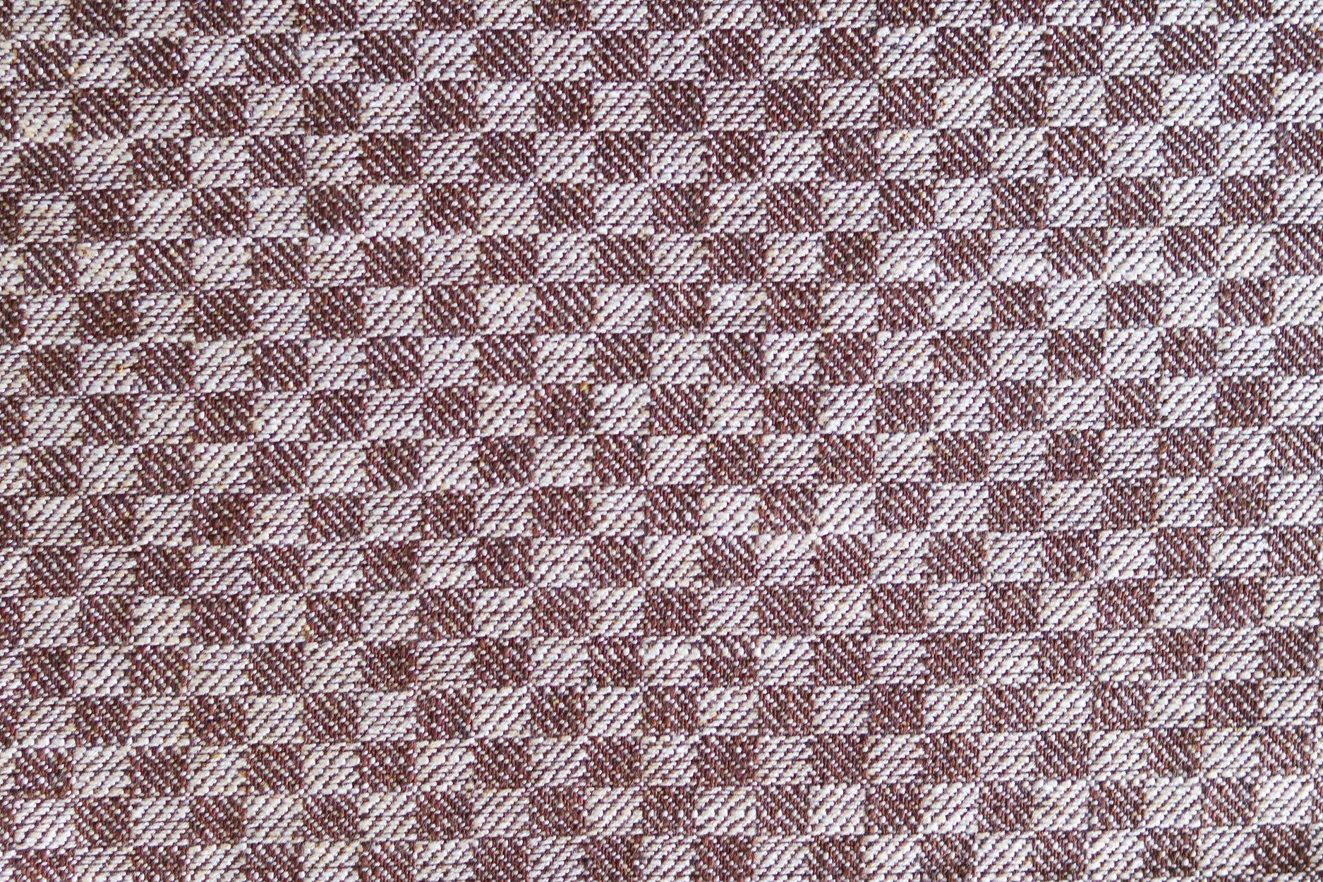 Close up of woven fabric with small scale checkerboard pattern in white and dark brown.