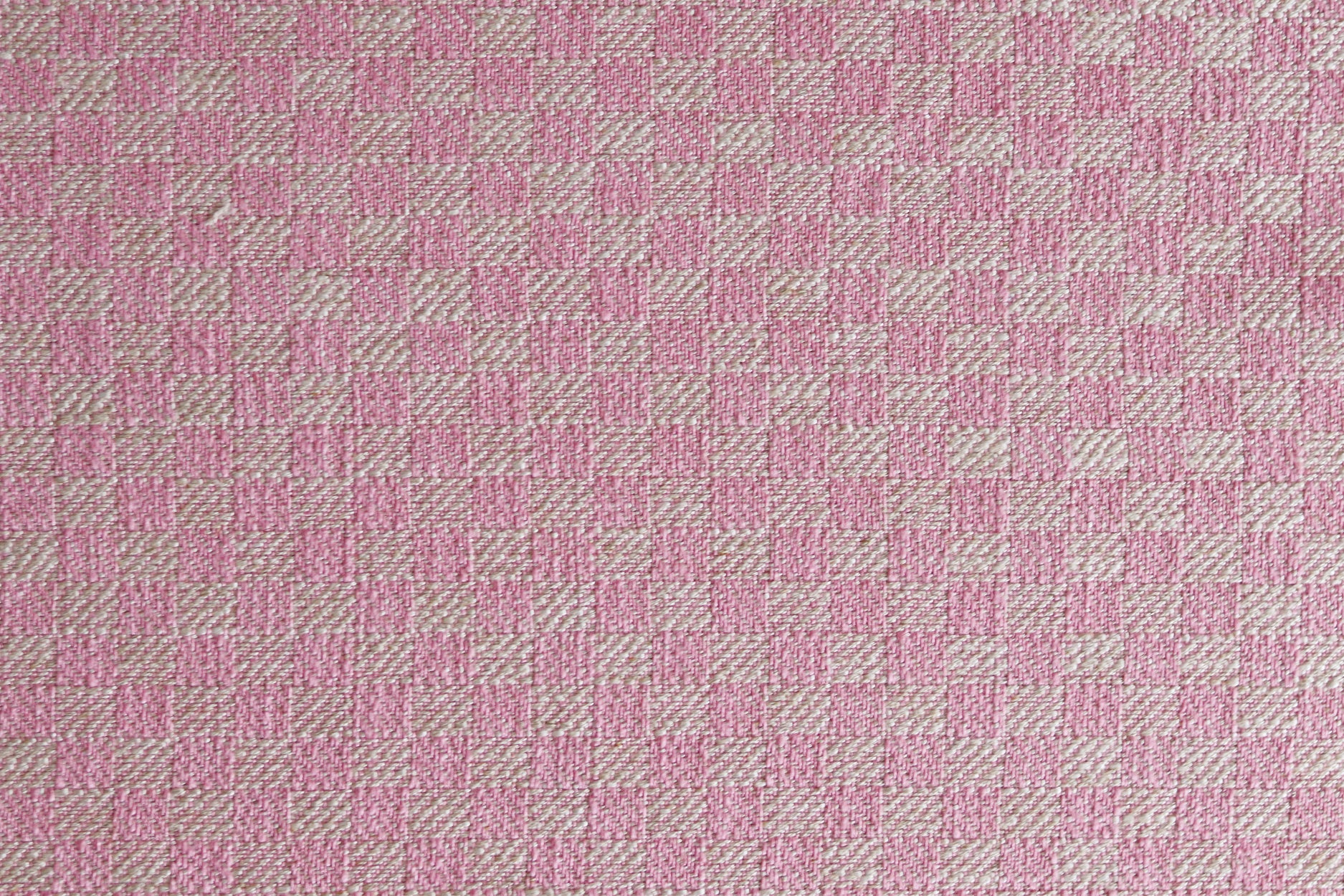 Close up of woven fabric with small scale checkerboard pattern in white and bright pink. 