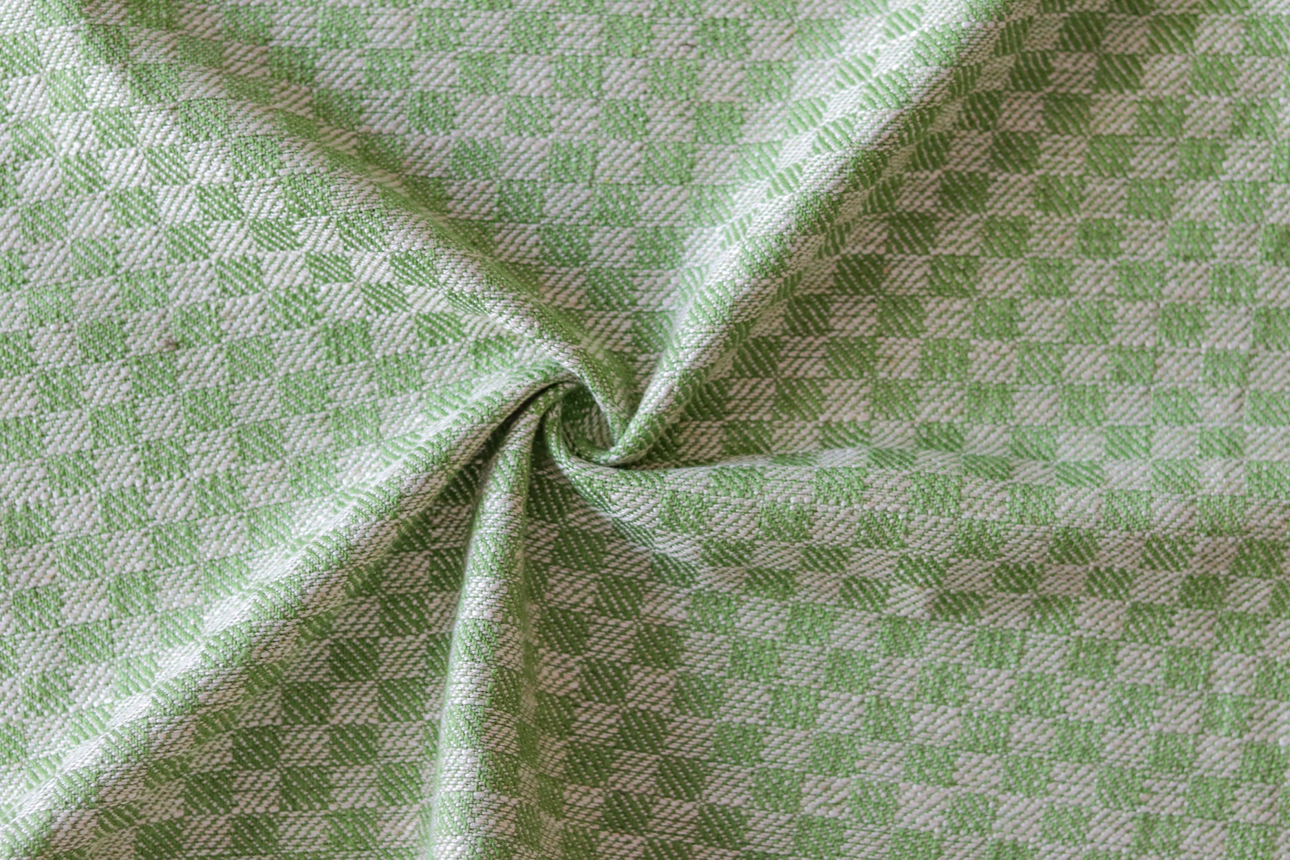 Close up of draped woven fabric with small scale checkerboard pattern in white and bright green. 