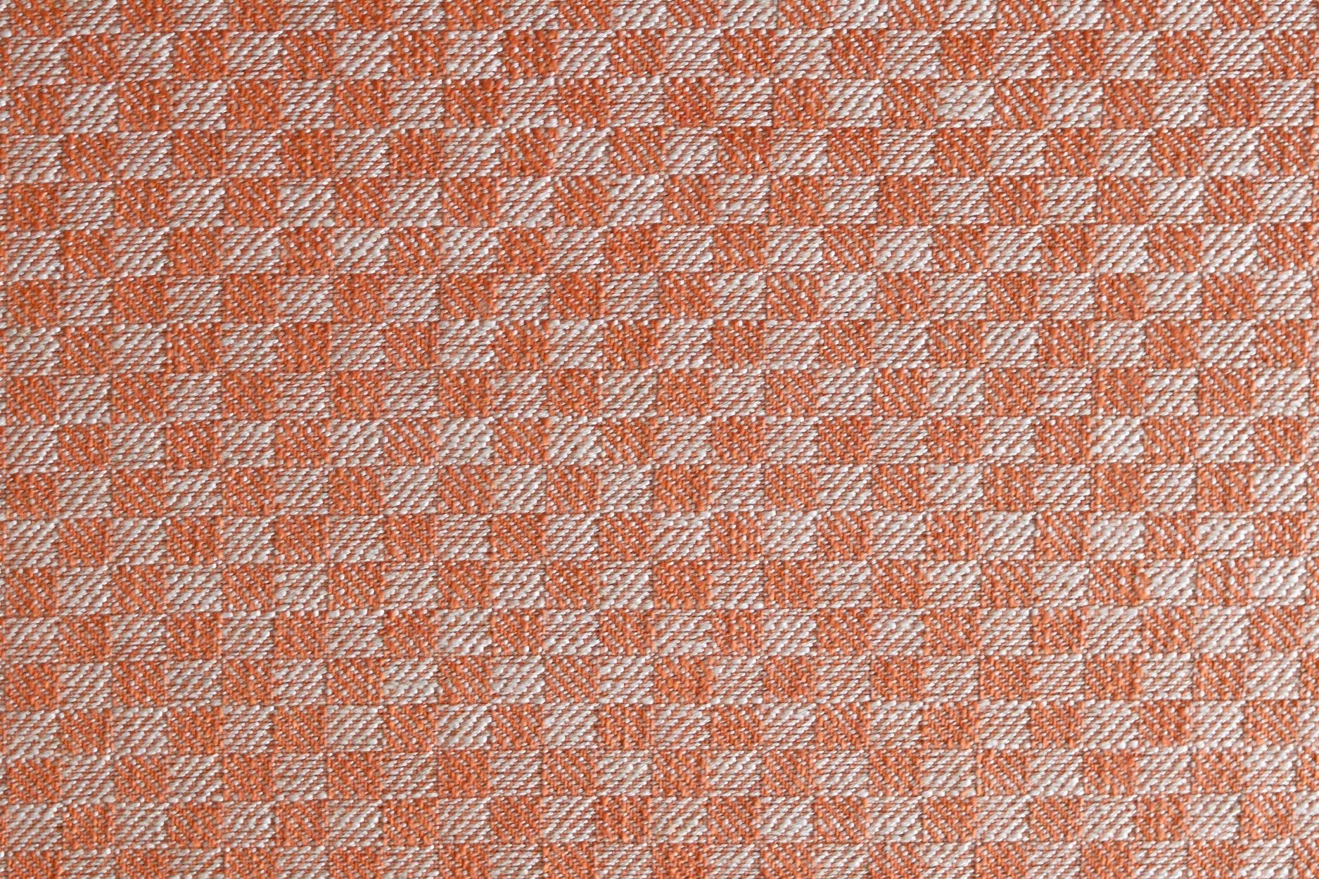 Close up of woven fabric with small scale checkerboard pattern in white and bright orange. 