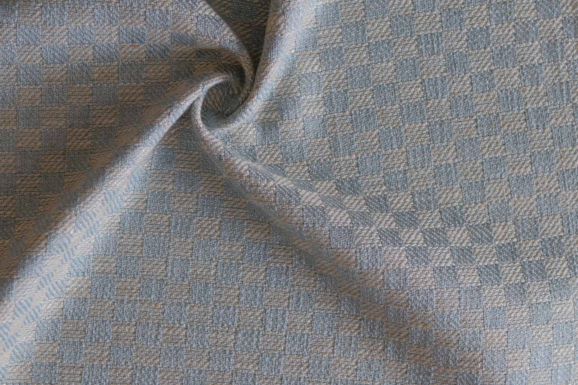 Close up of draped woven fabric with small scale checkerboard pattern in white and pastel blue.