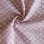 Close up of draped woven fabric with small scale checkerboard pattern in white and bubble gum pink.