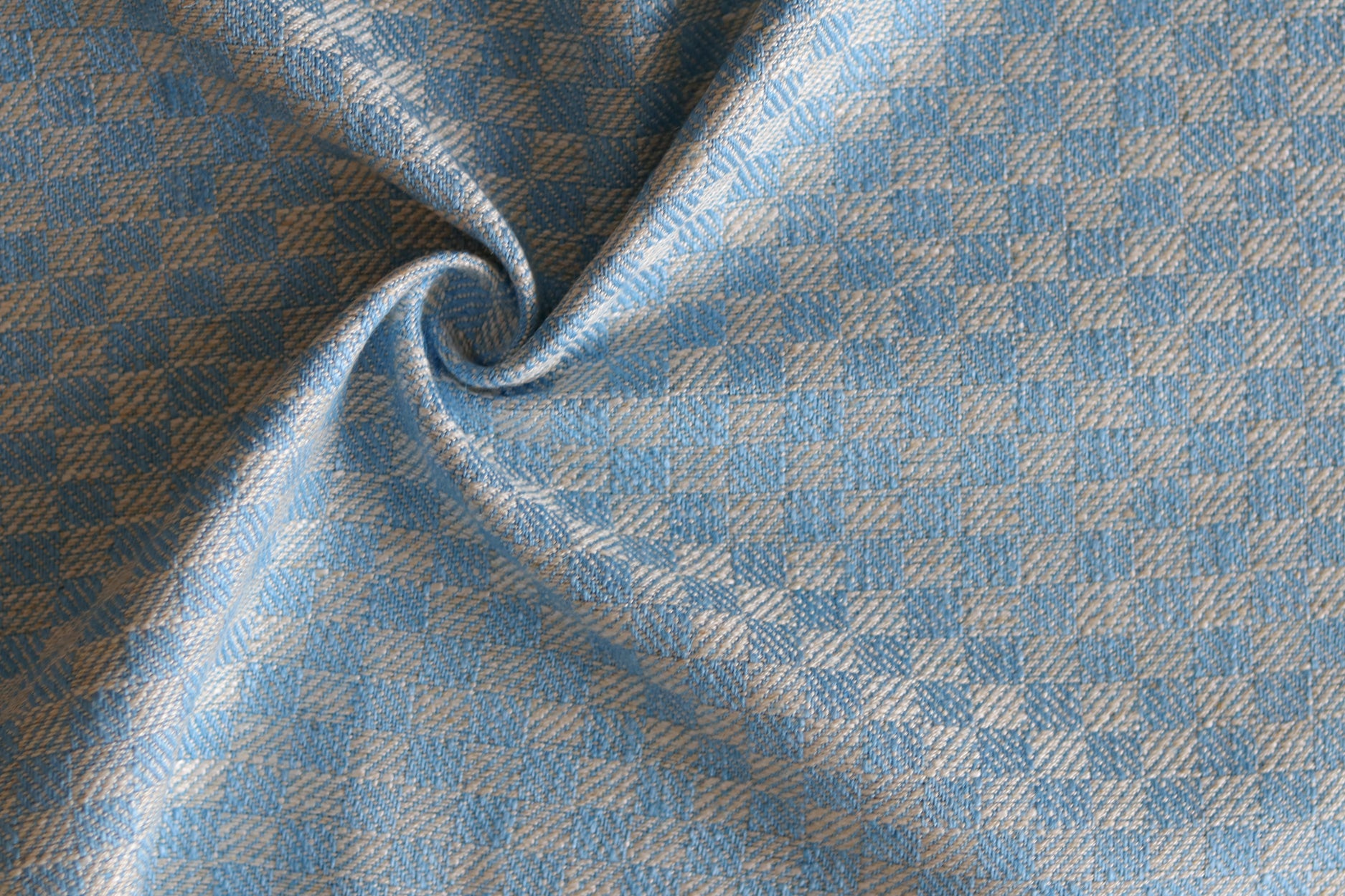 Close up of draped woven fabric with small scale checkerboard pattern in white and sky blue. 