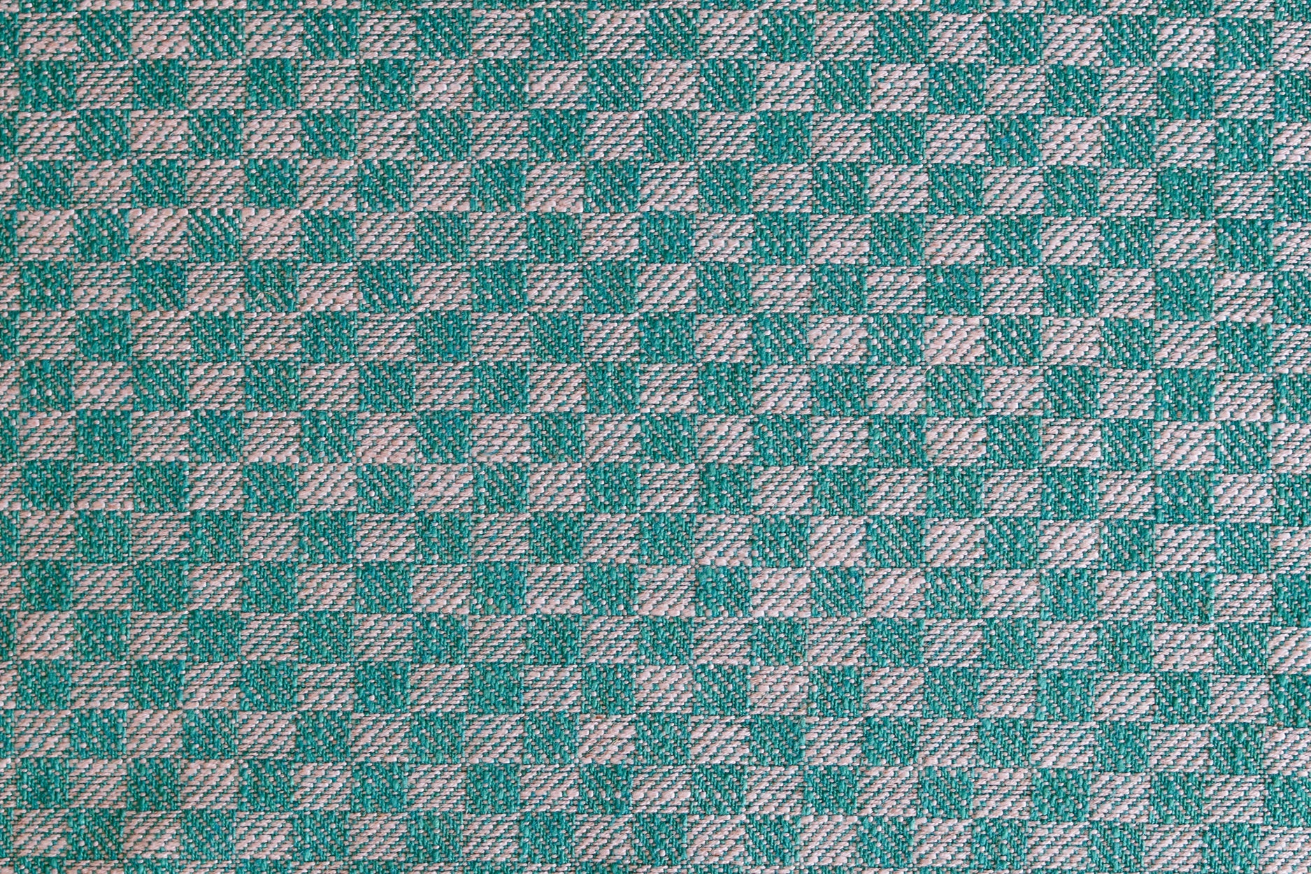 Close up of woven fabric with small scale checkerboard pattern in white and teal blue. 