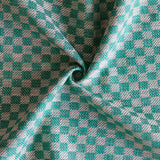 Close up of draped woven fabric with small scale checkerboard pattern in white and teal blue. 