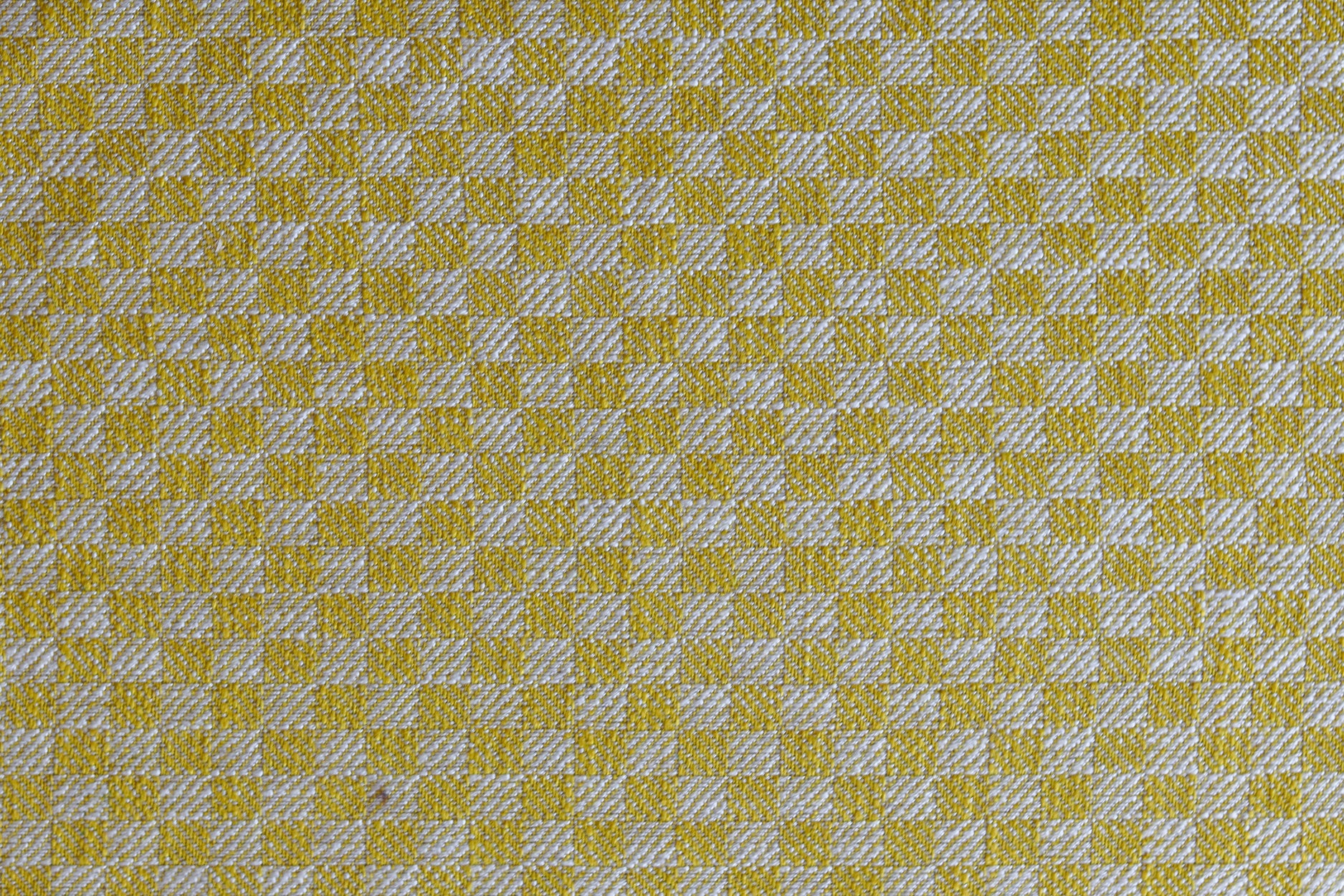 Close up of woven fabric with small scale checkerboard pattern in white and yellow.