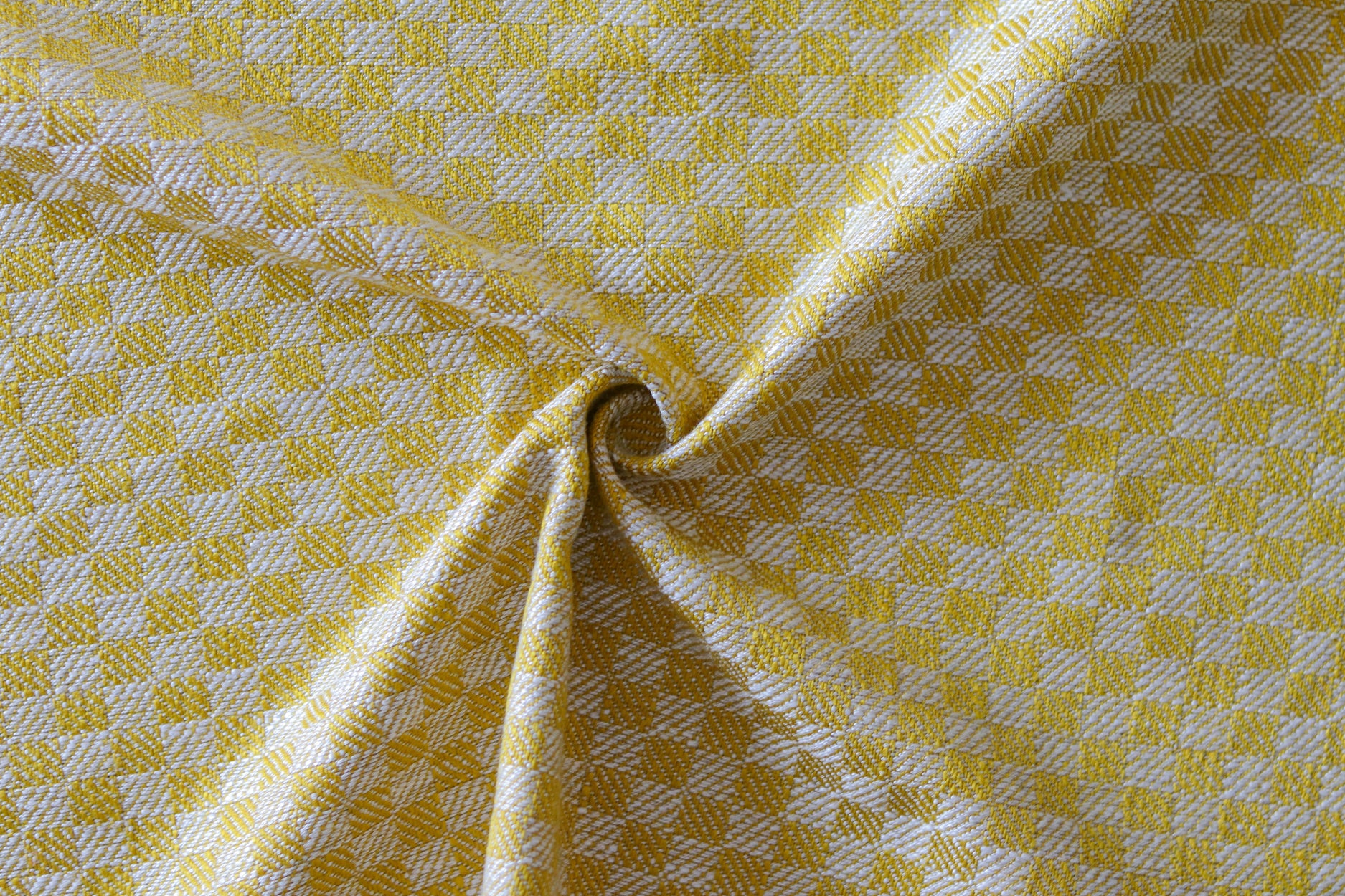 Close up of draped woven fabric with small scale checkerboard pattern in white and yellow.