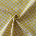 Close up of draped woven fabric with small scale checkerboard pattern in white and yellow.