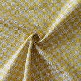 Close up of draped woven fabric with small scale checkerboard pattern in white and yellow.