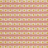 Detail of fabric in a playful dotted check print in pink and mustard on a cream field.