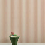 A green wooden stool with books and a mug against a Wallpaper playful hand drawn dotted stripe in blush.