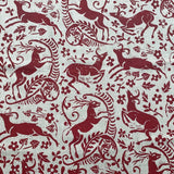Detail of fabric in a deer, leaf and flower print in red on a white field.