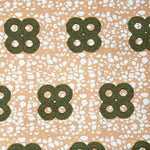Detail of fabric in a curvilinear print in green and brown on a mottled coral field.