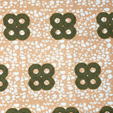 Detail of fabric in a curvilinear print in green and brown on a mottled coral field.