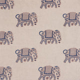 Detail of fabric in a repeating elephant print in maroon and blue on a cream field.
