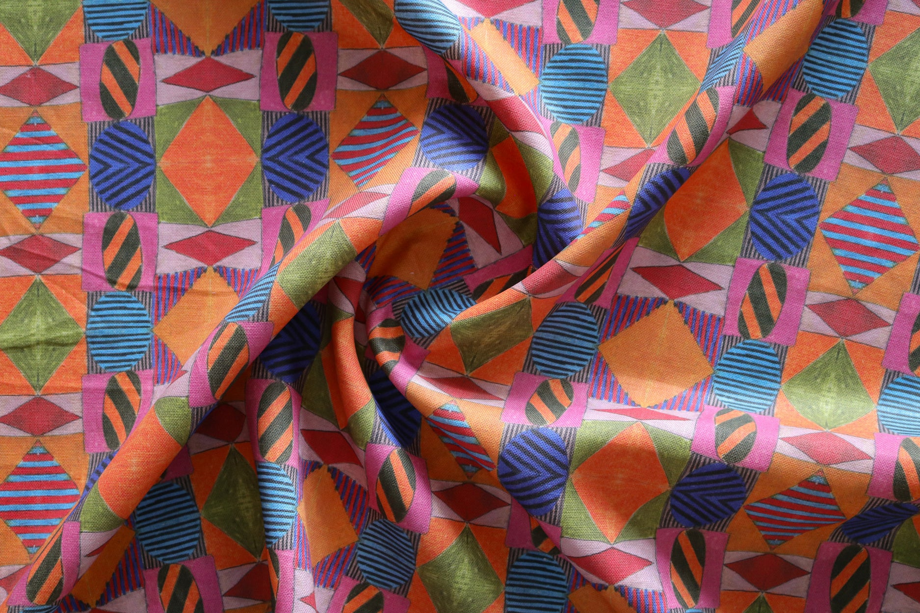 A close-up of draped fabric with a bold geometric pattern in orange, pink, blue, green and red.
