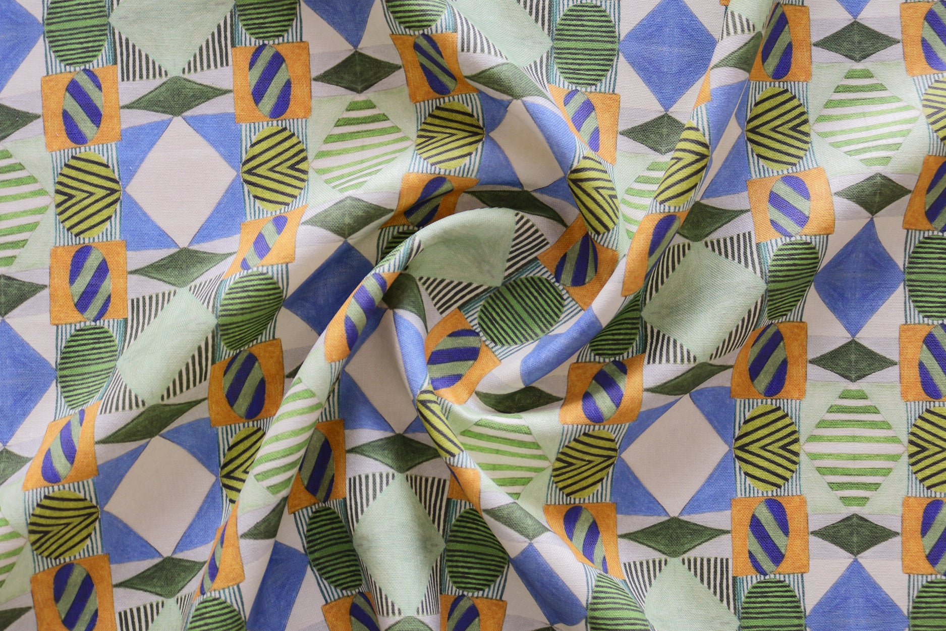 A close-up of draped fabric with a bold geometric pattern in blue, green, orange and white. 