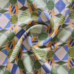 A close-up of draped fabric with a bold geometric pattern in blue, green, orange and white. 