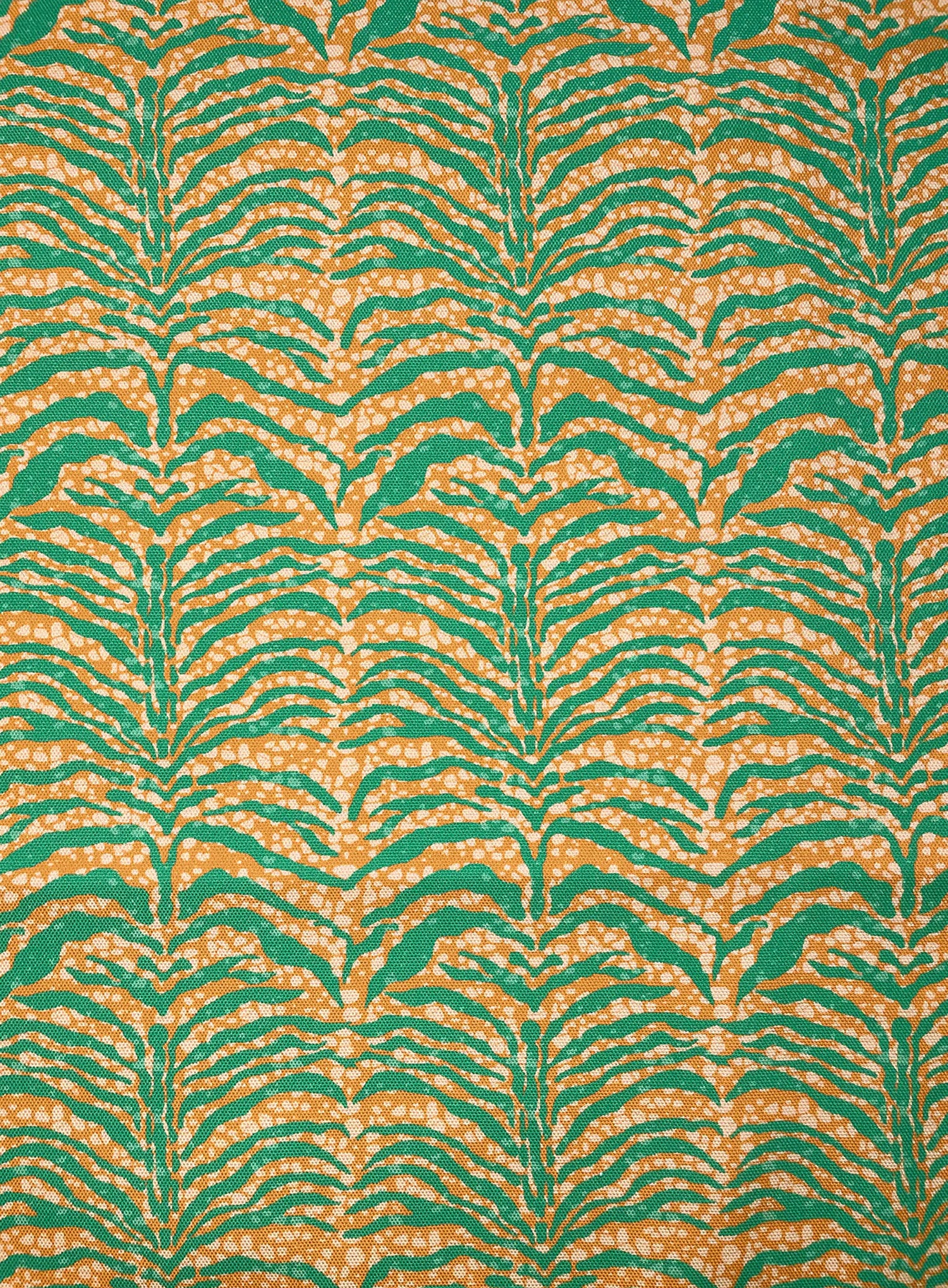 Detail of fabric in a linear botanical print in green on a mottled cream and orange field.